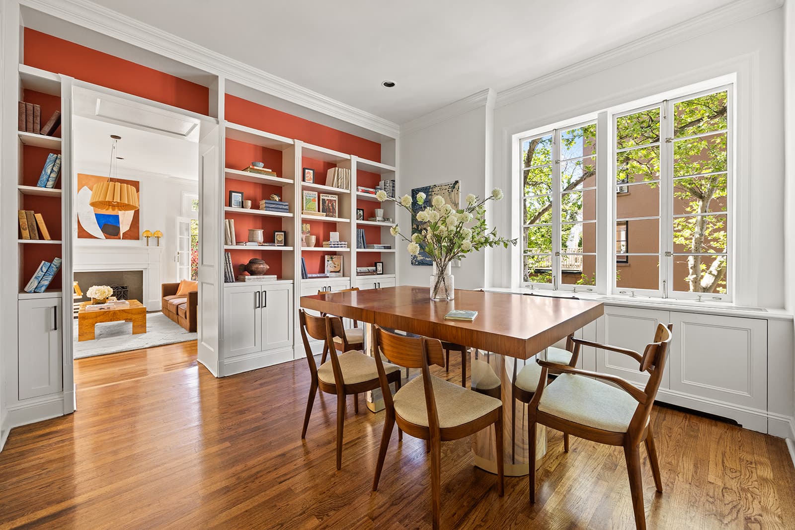 A dining room lined with red-backed bookshelves