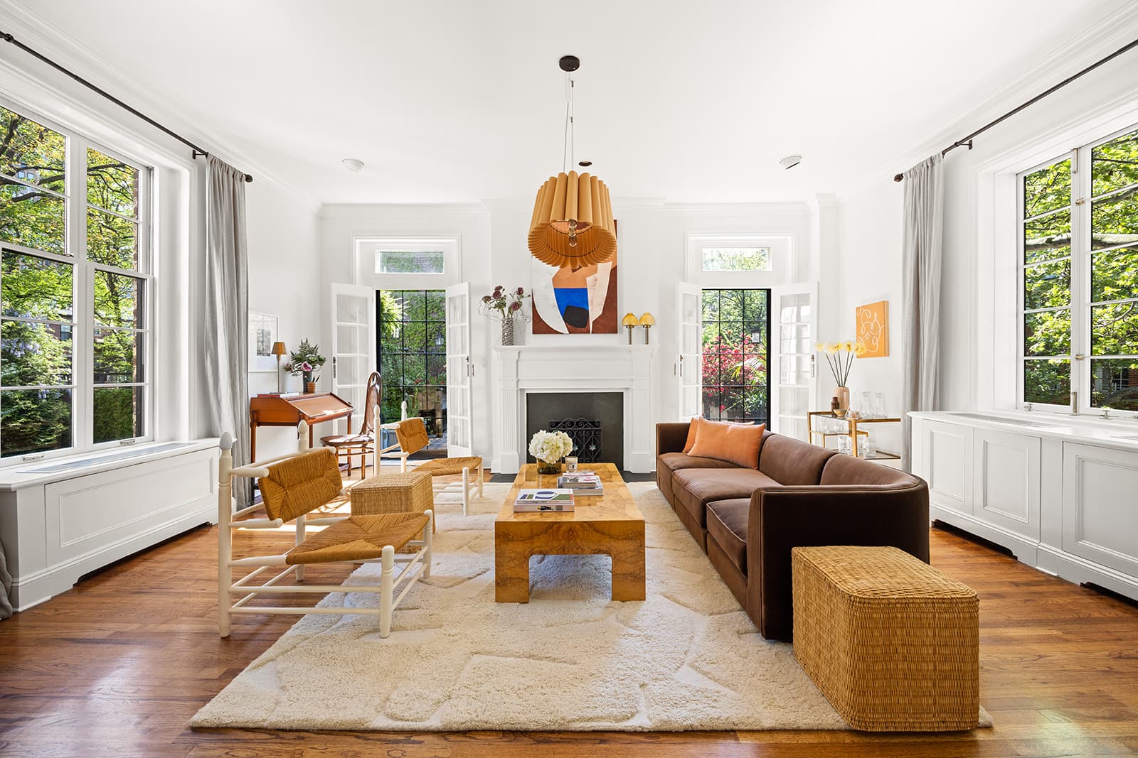 A sunlit living room with a fireplace between two sets of garden doors
