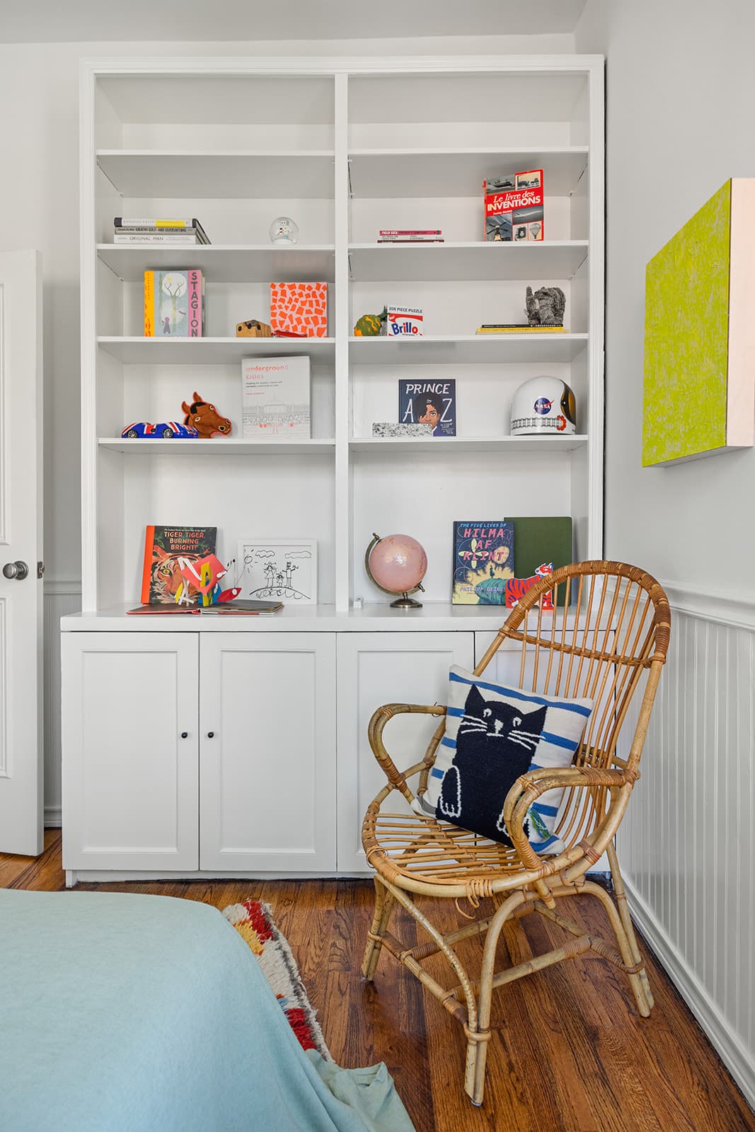A rattan chair in a reading nook beside built-in shelves