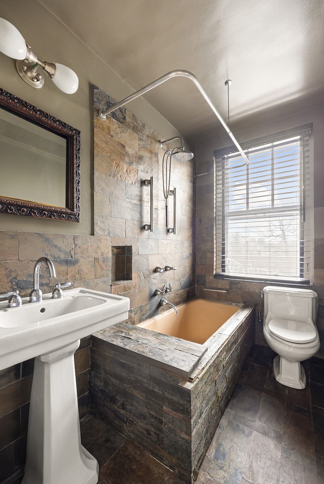 A pre-war bathroom with a tiled tub and pedestal sink