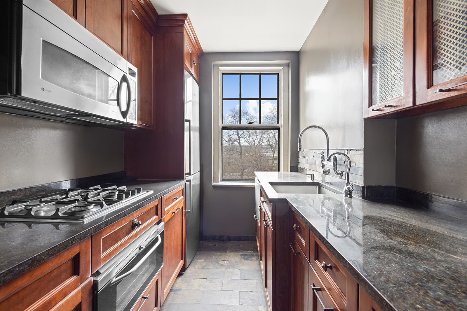 A galley kitchen with a window at the end
